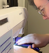 A person sewing purple fabric in a sewing machine.