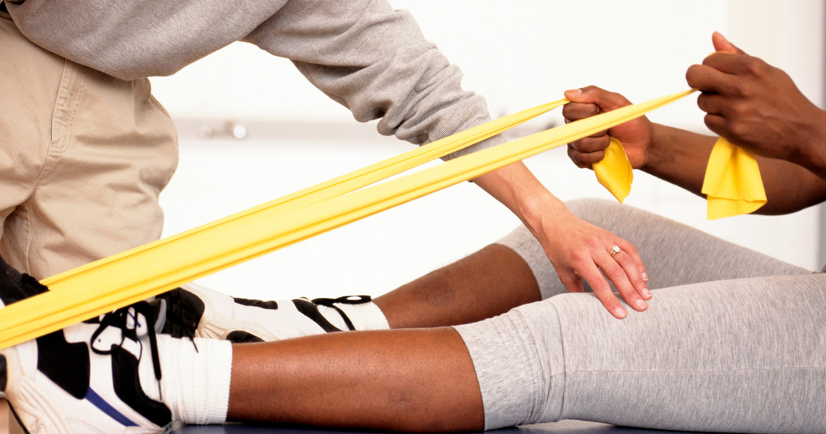 A person completing a simple resistance band exercise program at home, demonstrating how effective strengthening can be achieved without a gym.