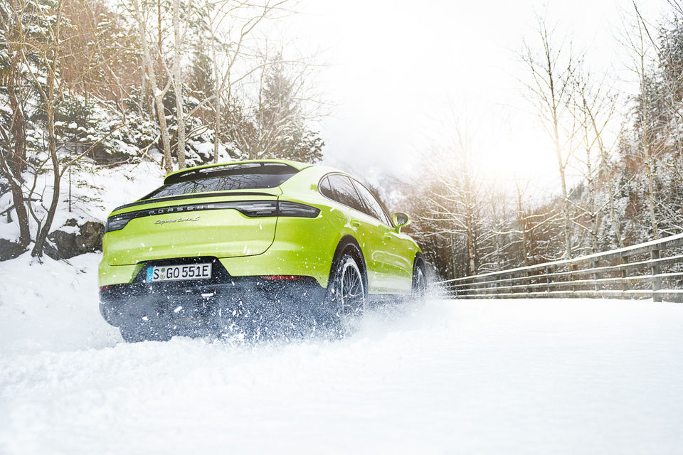 Ein Porsche Cayenne Turbo S in peridot, einem Hellgrün, fährt durch den Schnee