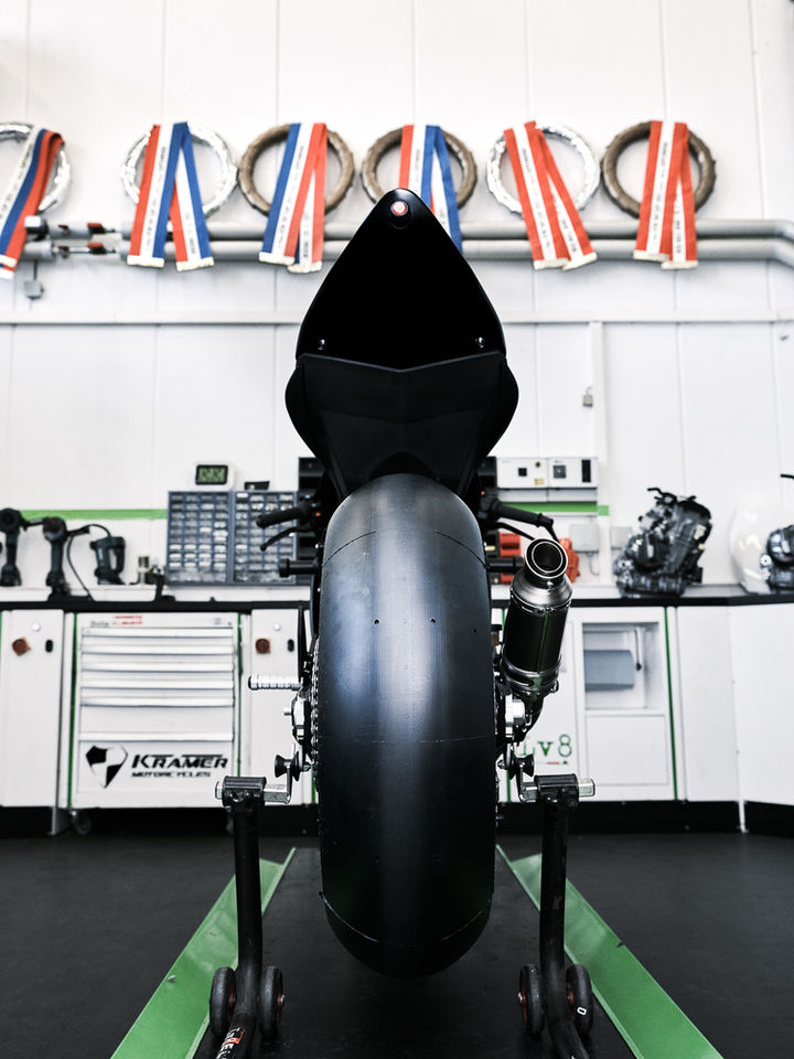 Rennmotorrad in Werkstatt, Rückansicht, Trophäen im Hintergrund