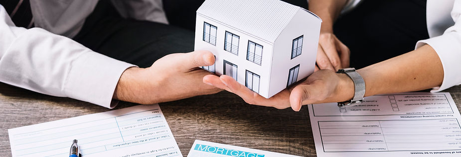 Two business people hold a paper house