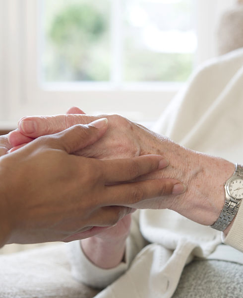 Close-up of a caregiver gently holding an elderly person’s hands.