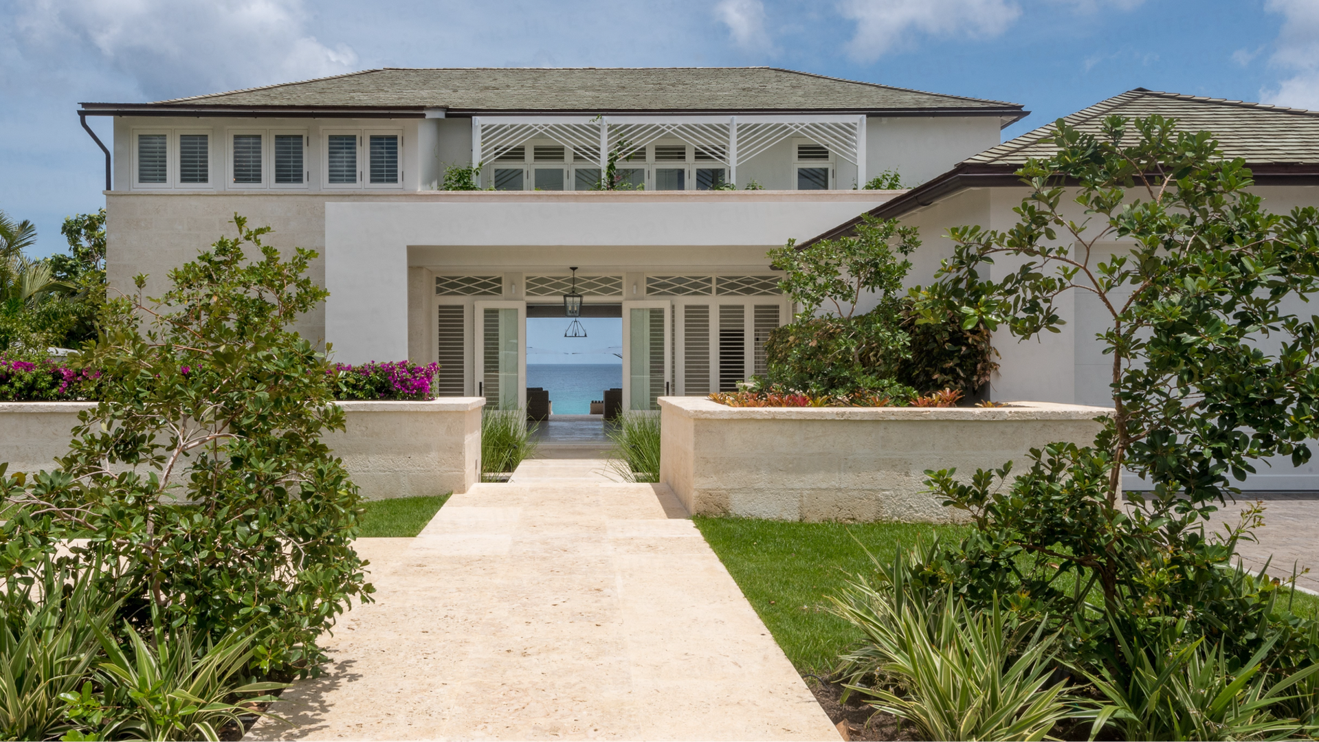 Villa Villakulla Barbados
An entry procession through courtyard garden and across a bridged Koi pond offer framed views of the turquoise Caribbean Sea through the house and across the infinity edge pool. Celebrating it’s West Coast beach front location, this holiday home has been designed with sea views from all rooms in the house.
Coral stone and timber detailing reference the traditional Barbadian vernacular and punctuate the clean lines of the house. A generous wrap around veranda provides shaded exterior living spaces and sheltered jalousie windows capture easterly breezes to naturally keep the house cool.