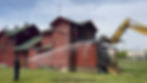 Building being demolished while man sprays with water