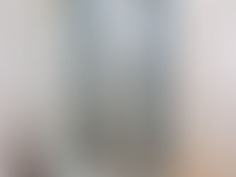 Glass shower with blue mosaic accents and marble tiles in a modern bathroom. Gold fixtures and wooden floor add elegance.