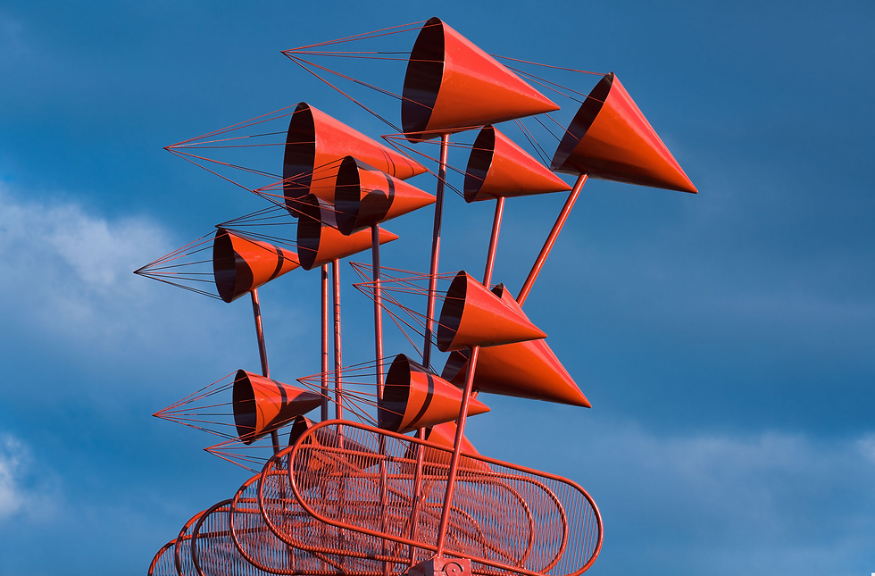 Sculpture created by Cesar Manrique : red cone-shaped on tall poles against a blue sky, with orange-red metal rails below and no visible text
