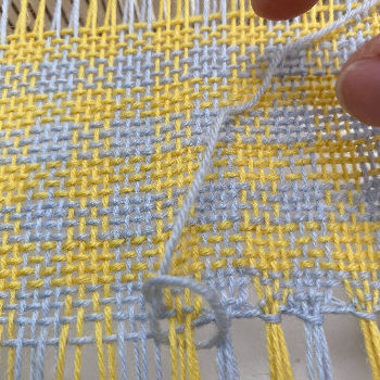 hemstitching on a rigid heddle loom using a needle and grey yarn