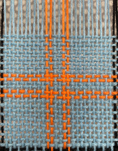 Blue woven fabric with intersecting orange threads forming a cross pattern. The texture and vibrant colors create a striking visual contrast.