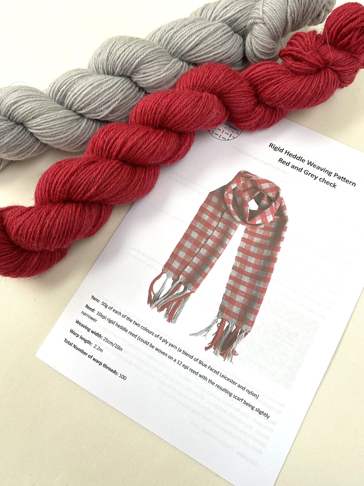 red and grey skeins of wool and instructions to weave a scarf