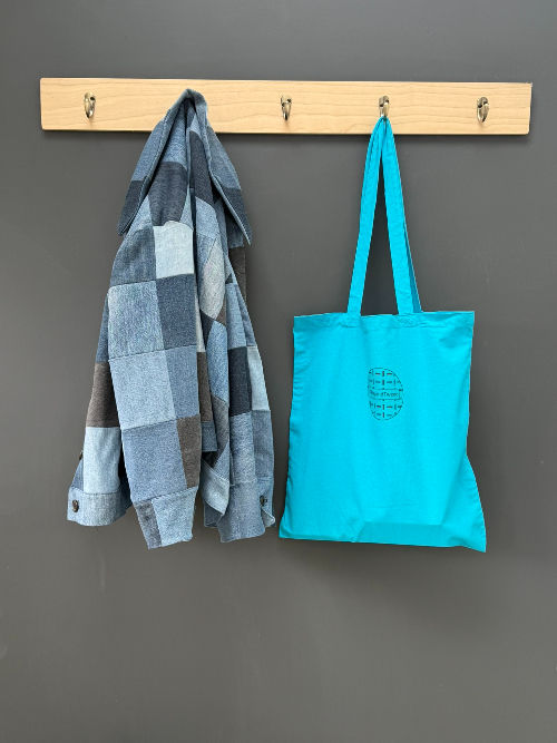 Thumbnail: branded tabbyandtweed bag hung up on a peg along side a jacket