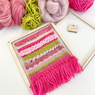 a pink and green textured weave on a square frame loom