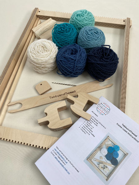 beige wooden frame loom with balls of wool