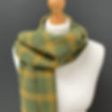 Green plaid scarf with yellow stripes draped on a white mannequin against a gray background, creating a cozy, stylish look.
