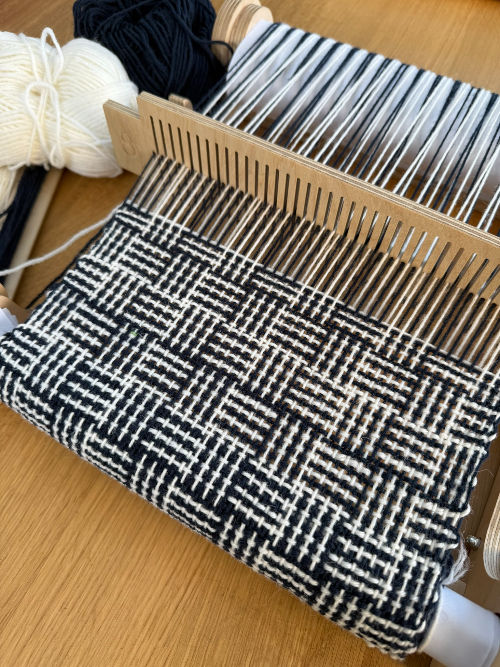 Thumbnail: navy and white woven scarf being woven on a rigid heddle loom