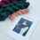 Thumbnail: teal and plum scarf weaving kit with skeins of yarn and pattern