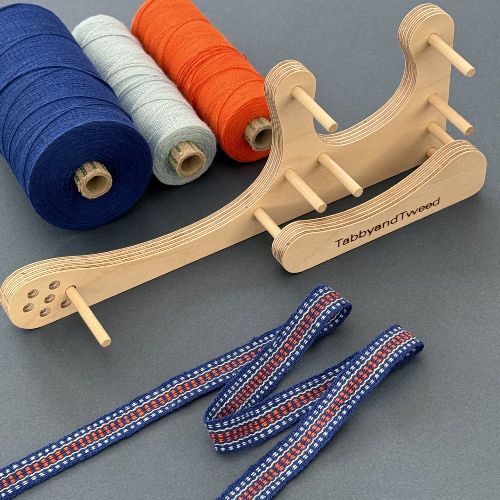 a tabbyandtweed inkle loom with handwoven braid and yarn