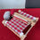 Thumbnail: rigid heddle weaving loom kit with a red and grey weave on it