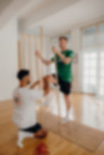 Auf dem Bild ist der erfahrene Therapeut Mohsen Salah Muhsin während einer individuell angepassten Sporttherapie mit dem ehemaligen BSG Chemie Leipzig Fußballspieler Alexander Bury zu sehen. Die Therapie findet in einem hellen, modern eingerichteten Raum statt, der eine angenehme und konzentrierte Atmosphäre bietet. Alexander Bury, gekleidet in einem grünen Sporttrikot, führt eine gezielte stabilisierende Übung mit Holzstäben durch, während Mohsen Salah Muhsin ihn mit fachkundiger Anleitung unterstützt und korrigiert. Diese innovative Bewegungs- und Rehabilitationsmethode fördert gezielt Koordination, Balance und Muskelaktivierung – essenziell für eine nachhaltige Regeneration nach Verletzungen oder intensive Leistungssteigerung im Sport. Die Therapie ist Teil des einzigartigen Re-Motion-Ansatzes, der auf die individuelle Regeneration und Bewegungsoptimierung spezialisiert ist. Besonders für Profisportler, ambitionierte Athleten und Rehabilitationspatienten.