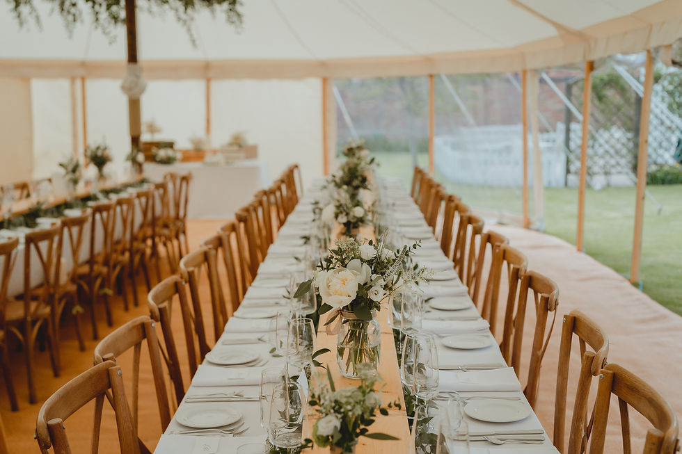 Wide trestle tables inside a Peacock and Bow pole and canvas marquee.