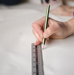 A Wills Marquees craftsperson marks out a pattern on canvas using a pencil and a metal ruler