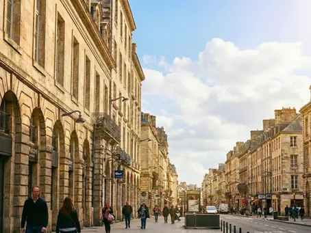 Rue de centre-ville en France, immeubles anciens en pierre et passants — illustration de l’investissement locatif et de la rénovation comparant le dispositif Jeanbrun et le Denormandie..
