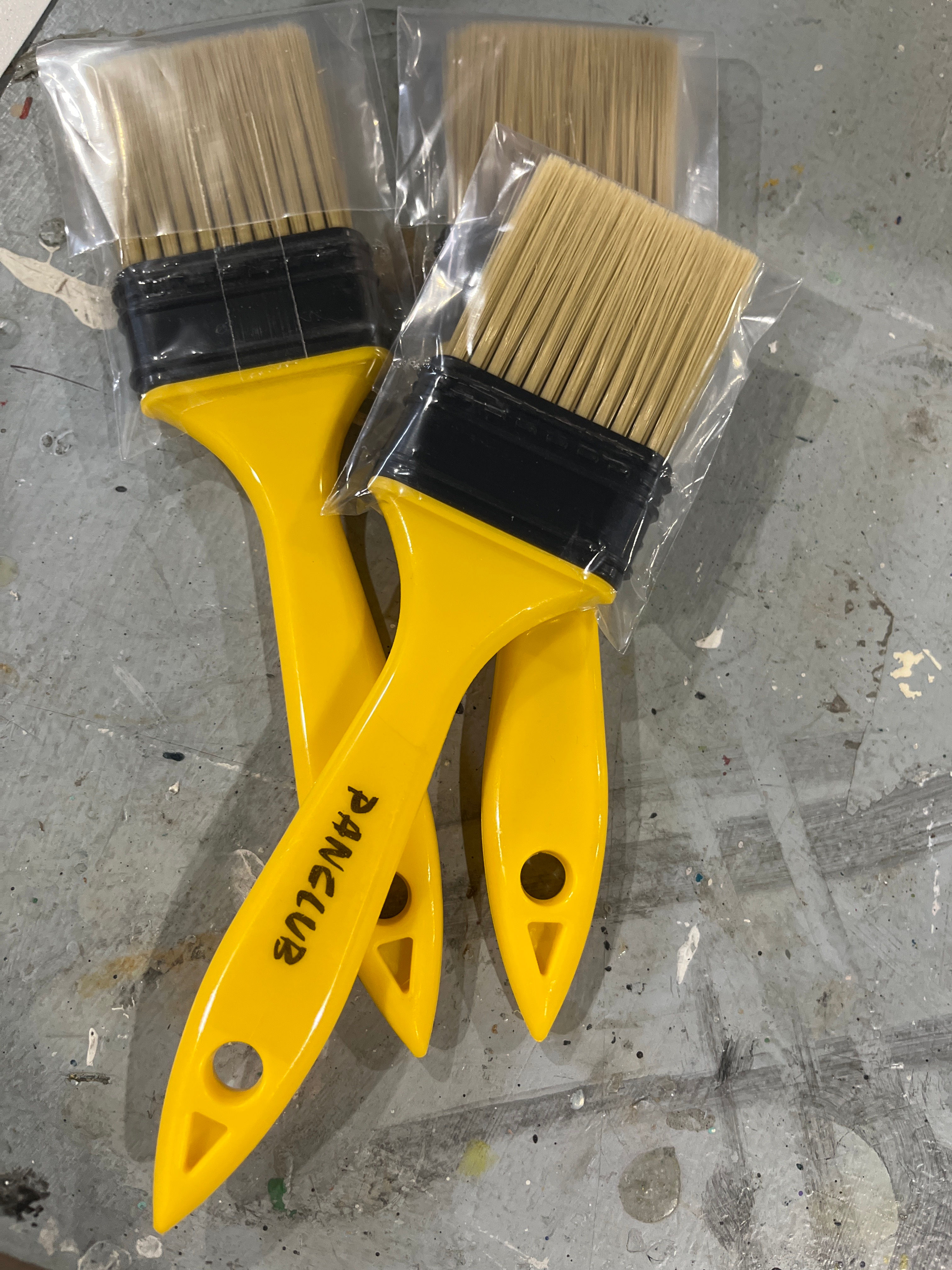New yellow PANCLUB paint brushes in plastic packaging, ready for use.