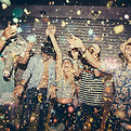 Group of adults celebrating with drinks and confetti