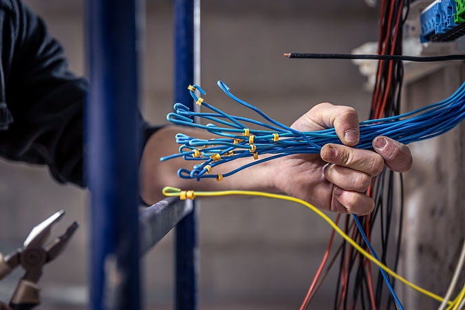 male-electrician-works-switchboard-with-electrical-connecting-cable.jpg