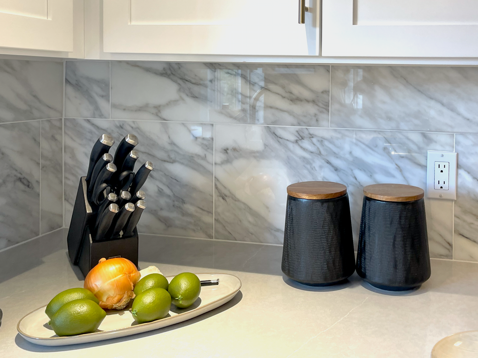 Staging decor for the kitchen included black accents to contrast with marble backsplash.