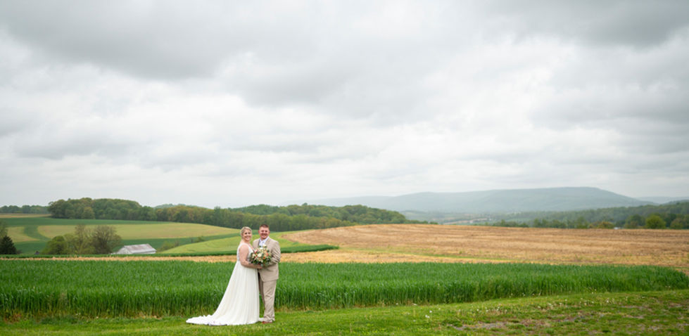 newlyweds posing by the wide open fields and sky of pa