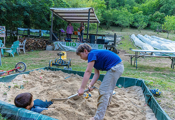 Enfant jouant dans un bac à sable à M'bio Jardin
