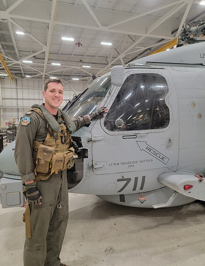 Pre-Mortem Labs founder and Navy helicopter pilot standing in front of an aircraft, highlighting background in aviation