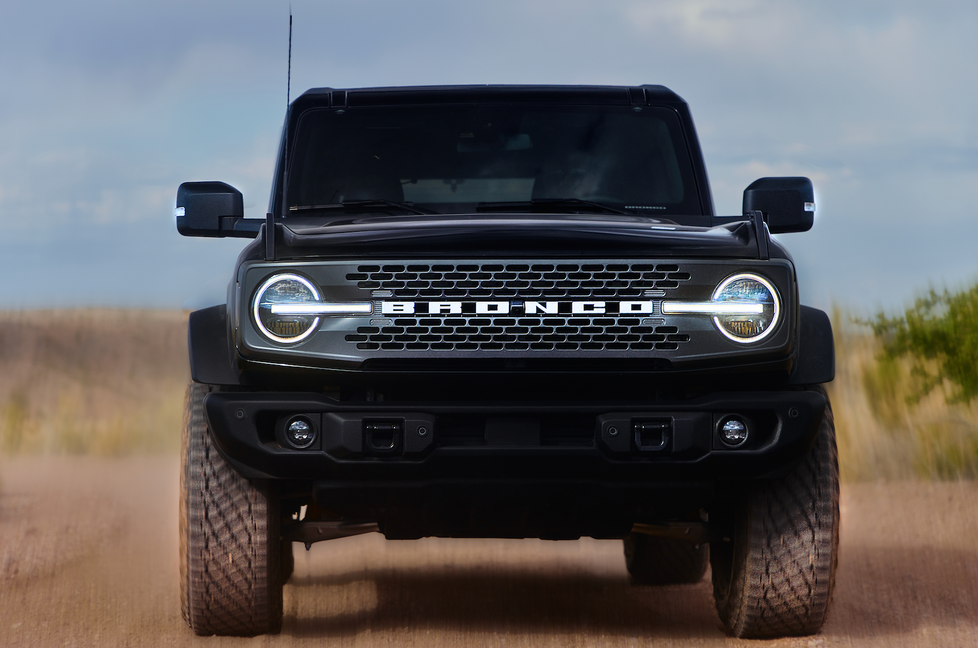 a black bronco is driving down a dirt road