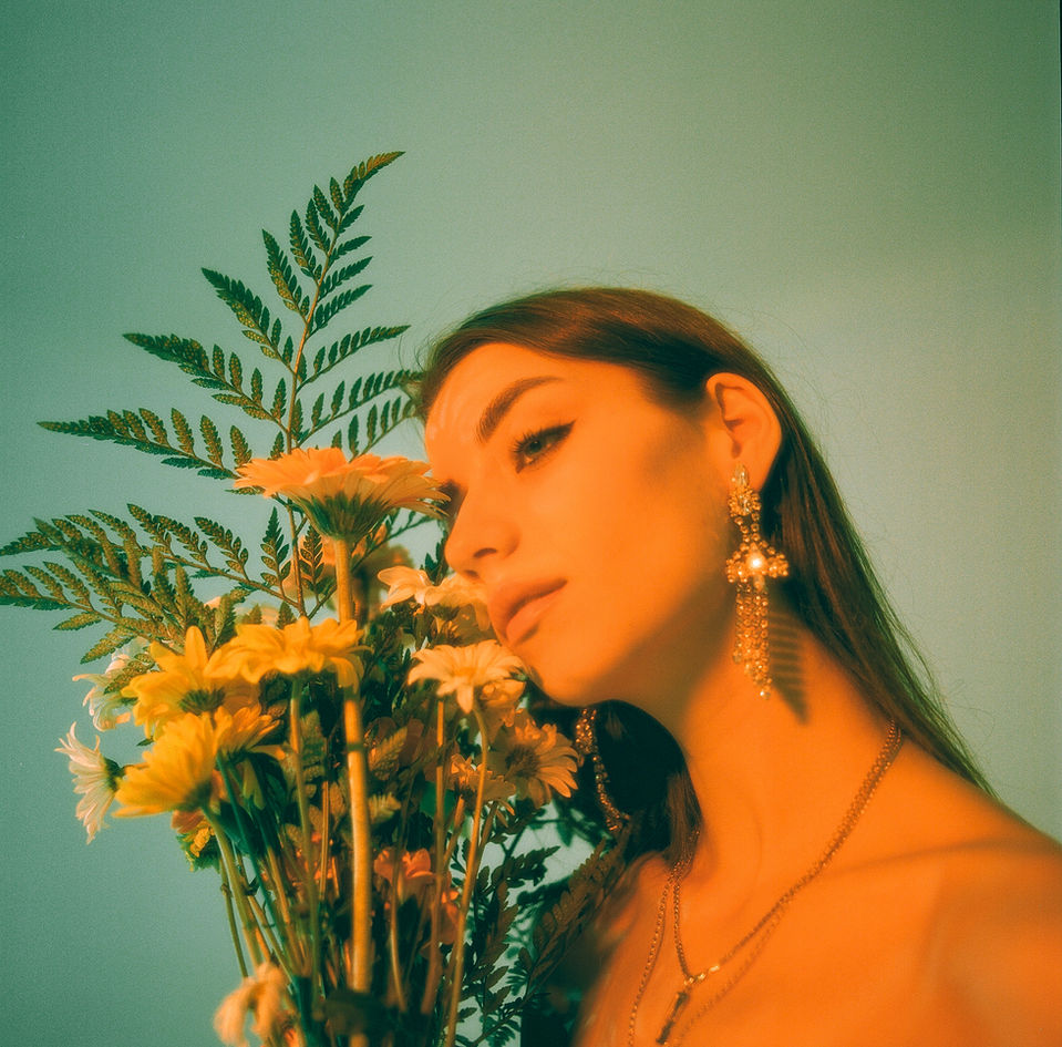 a woman wearing earrings holds a bouquet of flowers