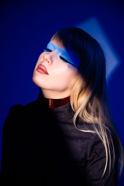 a woman wearing a choker and blue eye makeup looks up