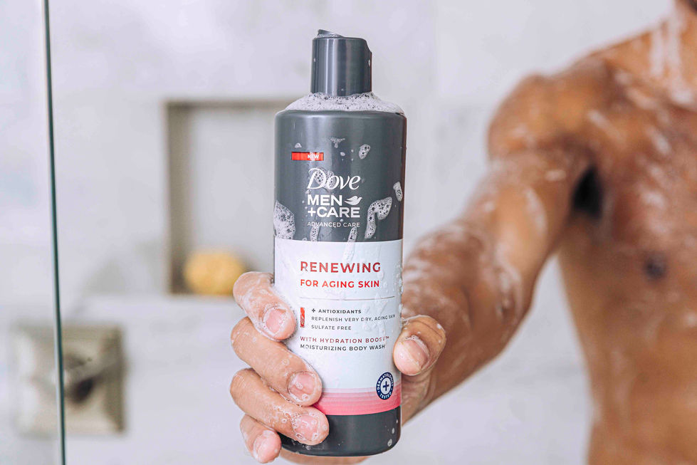a person holding a bottle of dove men + care renewing for aging skin