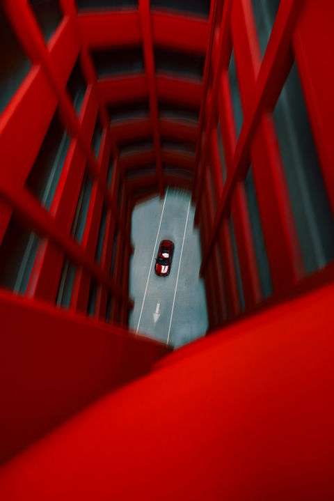 a red car is driving down a road with an arrow pointing to the right