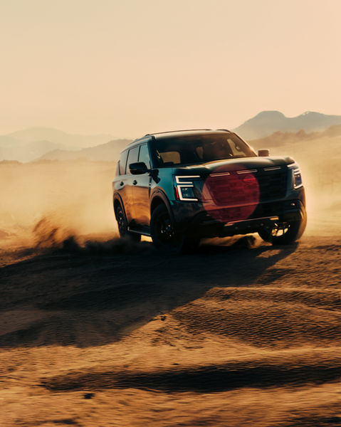 a black suv is driving on a dirt road