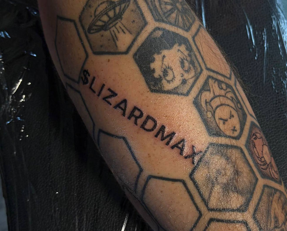 Close-up of a forearm tattoo that says $LIZARDMAX inside hexagon pattern