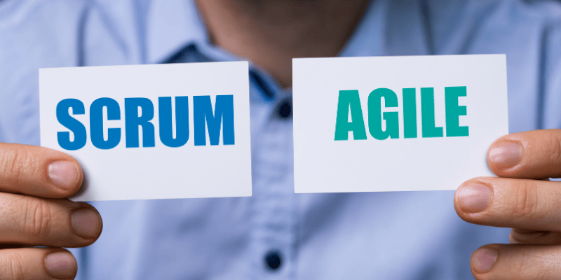 Person holding two cards labeled 'SCRUM' and 'AGILE', symbolizing the connection between Agile methodologies and the Scrum framework in project management and consulting.