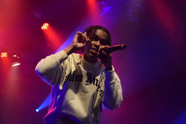 Young man singing into a microphone with stage lights behind him