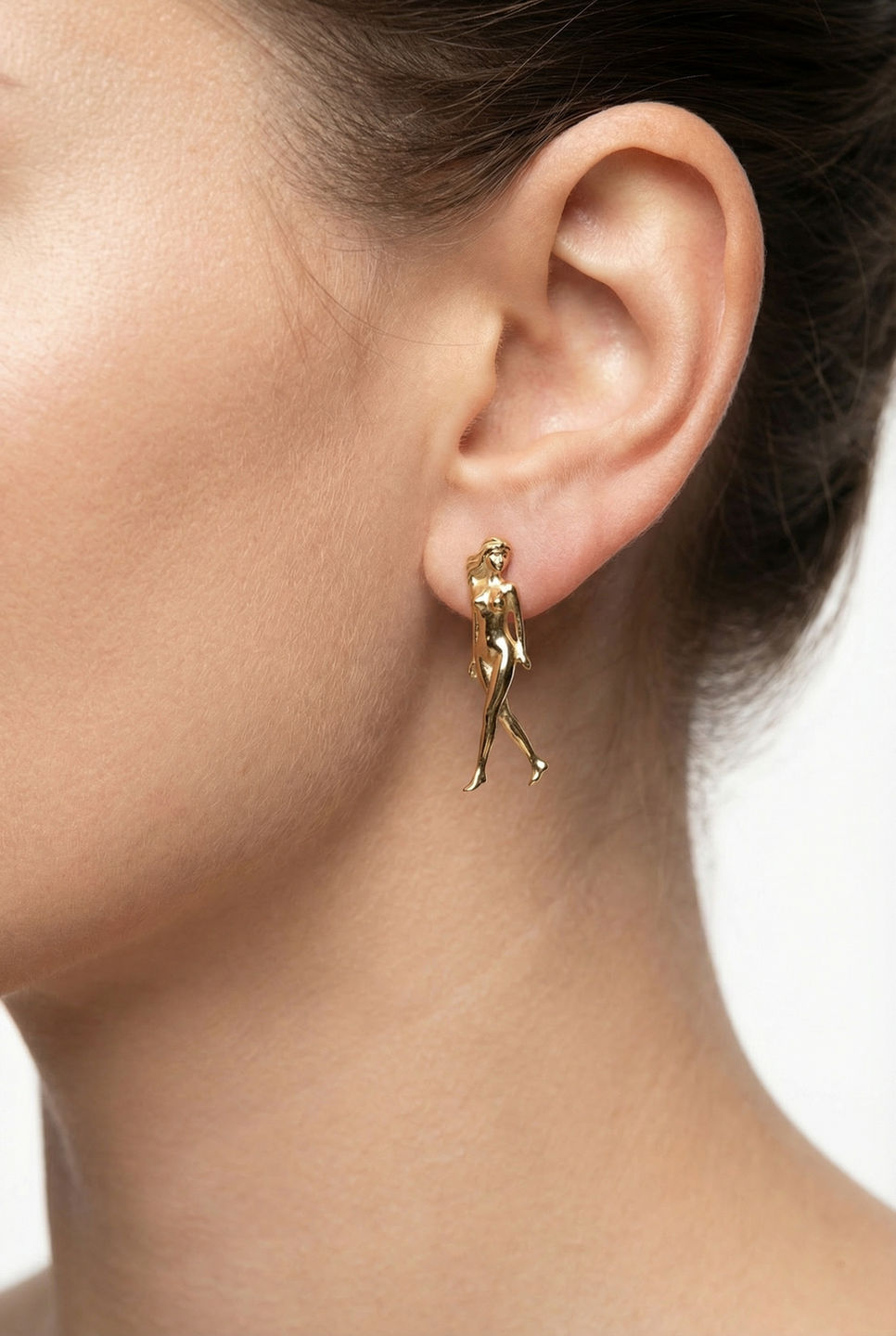 Female body earrings in gold with female form design on white background