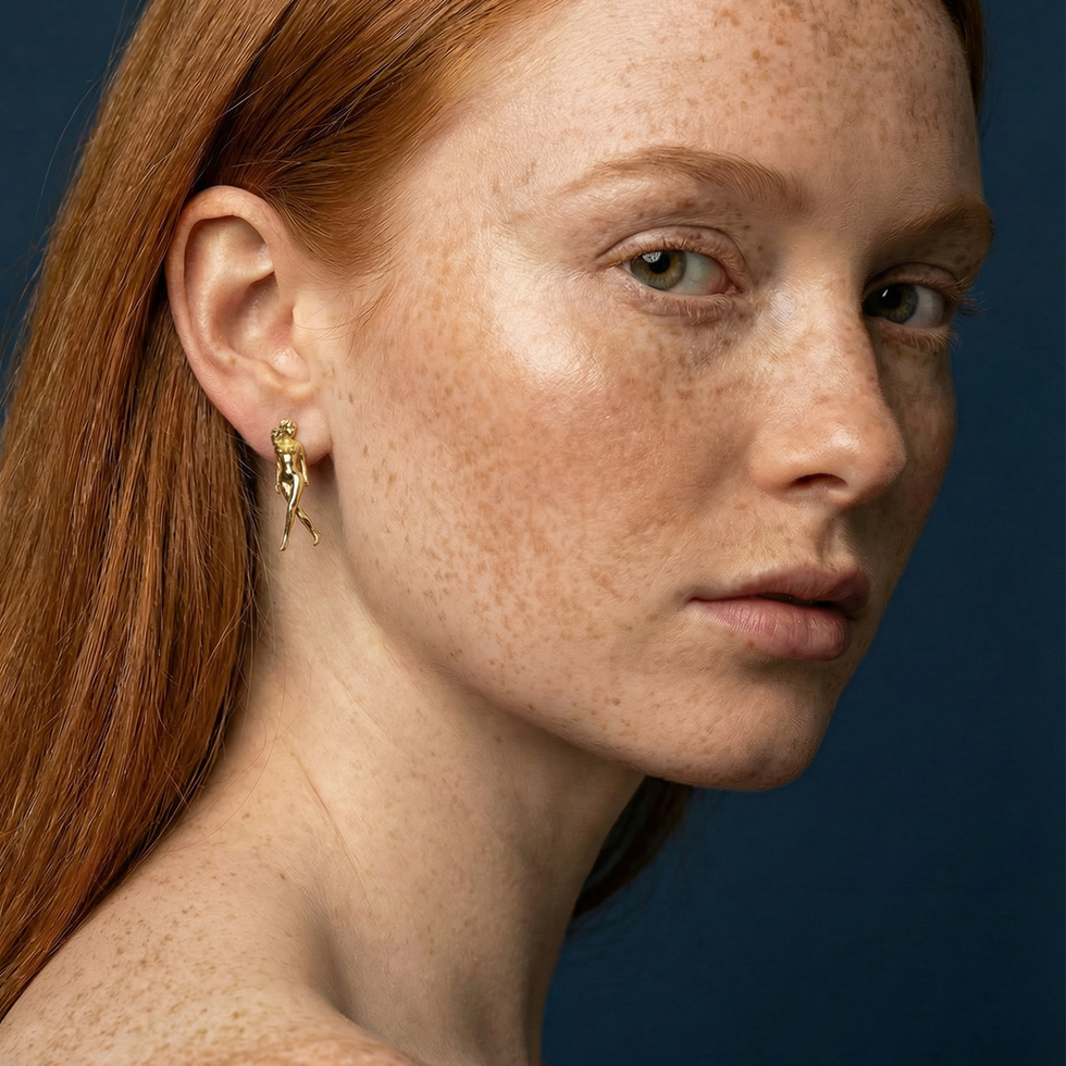 Model wearing female body earrings in gold inspired by the female form