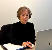 Mature woman working attentively on a silver laptop at an office desk.