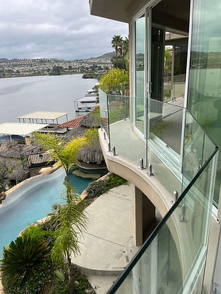 Glass balcony railing overlooking pool and lake