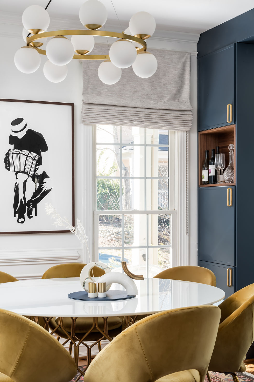 Elegant dining room with art, a round table, and a stylish chandelier.