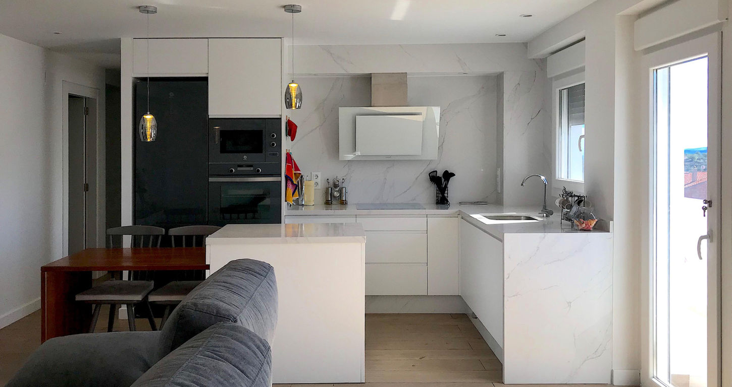 Cocina en L con mobiliario blanco integrada al salón en vivienda unifamiliar diseñada por Genovés Calleja Arquitectos.