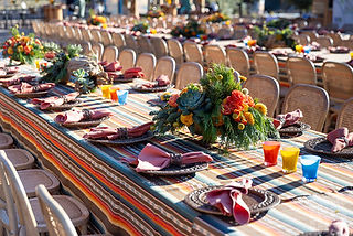 Outdoor dining activation with rustic woven chairs, striped linens, and vibrant floral centerpieces at Verkada Builders Camp.