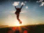 Personne sautant en l'air devant un soleil