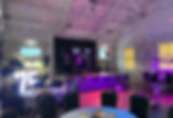 Party scene with stage, ballons and purple tinted lighting.